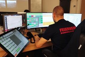 Mitarbeiter am Ausweicharbeitsplatz. Vor ihm sind drei Bildschirme.