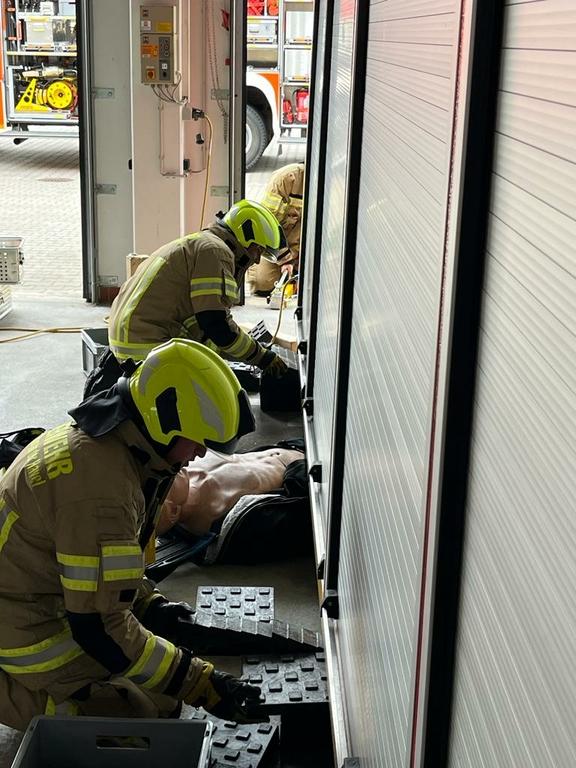Zwei Feuerwehrmänner sichern einen Container, um eine eingeklemmte Puppe zu retten.