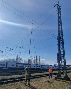Feuerwehrmann hat eine lange Stange in der Hand, die er zu Oberleitung der Bahn führt
