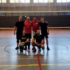 6 Volleyballer der Feuerwehr. Eine Frau hat den Ball in der Hand.