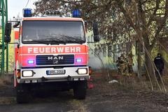 Feuerwehrauto steht am Baum. Im Hintergrund ist Rauch zu sehen.