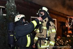 Feuerwehrmänner mit Atemschutz. Hier hilft ein Kamerad einem Kollegen beim Aufsetzen der Maske.