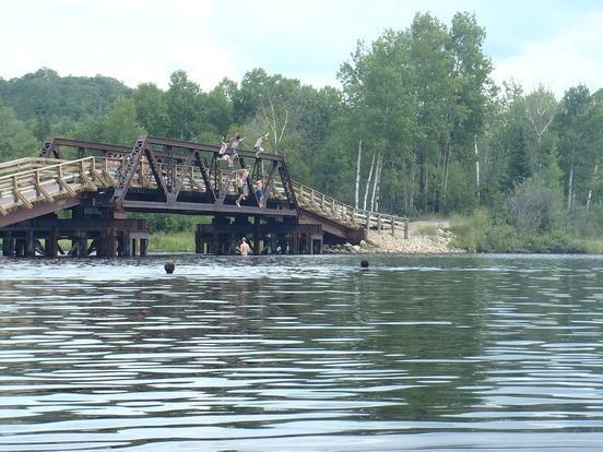 Brücke über dem Wasser. Davor schwimmende Leute.