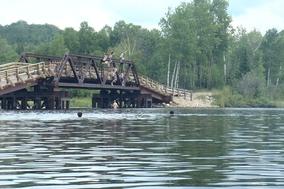 Brücke über dem Wasser. Davor schwimmende Leute.
