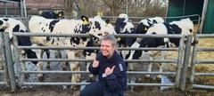 Frau hockt vor mehreren Kühen