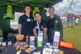 Drei Frauen am Stand unter einem Zelt