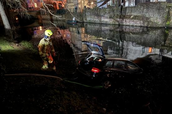 Auto im Wasser an Seilwinde. Daneben ein Feuerwehrmann