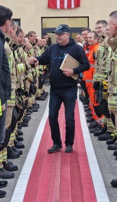 Feuerwehrmänner stehen Spalier. Mittig klatsch einer ab