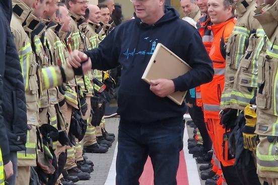Feuerwehrmänner stehen Spalier. Mittig klatsch einer ab