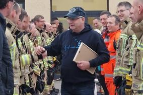 Feuerwehrmänner stehen Spalier. Mittig klatsch einer ab