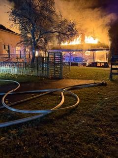 Brennender Dachstuhl, vorn liegen Schläuche