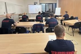 Disponenten im Schulungsraum an Tischen.