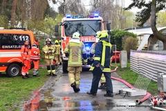 Feuerwehrmänner im Einsatz vor ihren Fahrzeugen.
