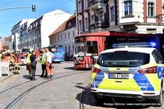 Polizeiauto, dahinter defekte Tram und Menschen