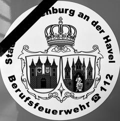 Logo der Feuerwehr in schwarz-weiß, mit Trauerflor