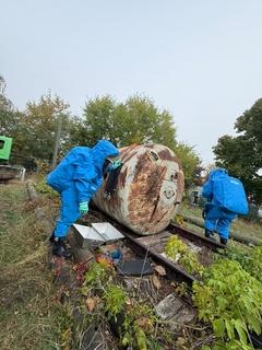 zwei Männer in blauen Schutzanzügen am Chemiefass