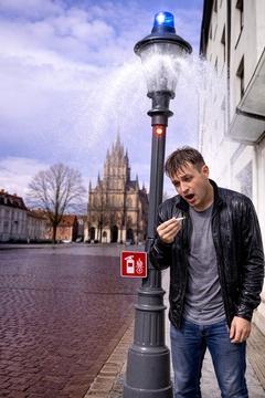 Laterne aus der Wasser spritzt mit Blaulicht und einem Mann mit Zigarette in der Hand, der nass wird
