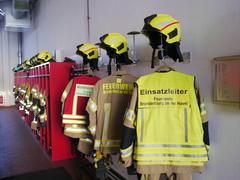 mehrere Jacken der Feuerwehrmänner mit unterschiedlichem Dienstgrad
