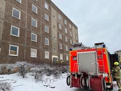 Wohnblock, davor ein Feuerwehrauto und es liegt etwas Schnee