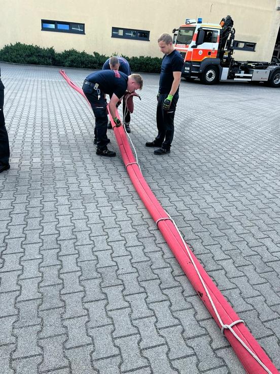 Drei Schläuche werden von Feuerwehrmännern zusammengebunden