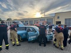 Kameradinnen und Kameraden an einem E-Fahrzeug