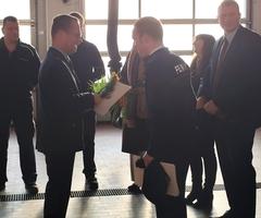 Übergabe der Schulterstücke, mehrere Männer sind fröhlich in der Fahrzeughalle