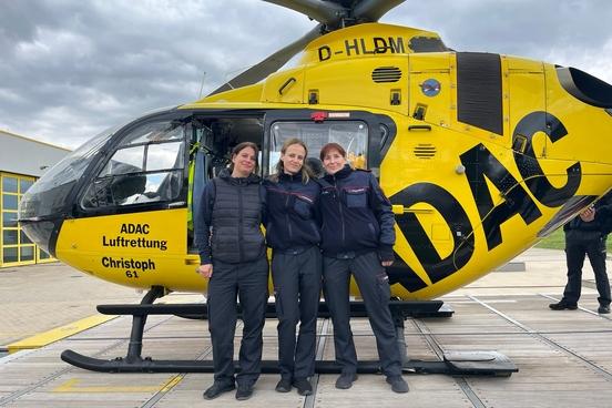 3 Frauen vor eine Rettungshubschrauber im ADAC Design
