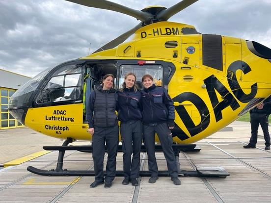 3 Frauen vor eine Rettungshubschrauber im ADAC Design