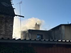 Hausdach und aufsteigender Rauch. Der Himmel ist blau.