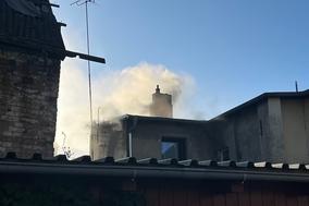 Hausdach und aufsteigender Rauch. Der Himmel ist blau.