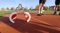 Startblock auf einer roten Tartanbahn, im Hintergrund Beine