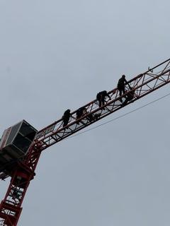 Männer hängen am Baukran in luftiger Höhe