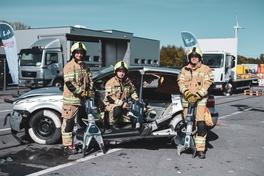 Gruppenbild am kaputten Fahrzeug mit Geräten in den Händen