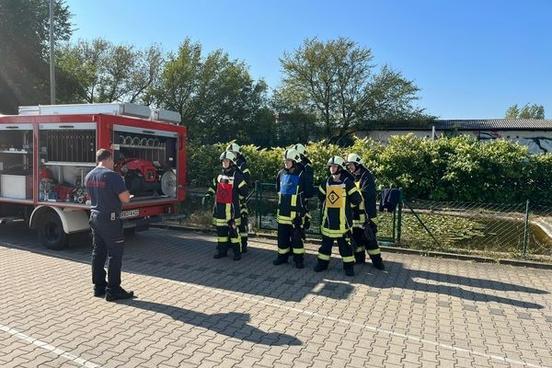 Ausbilder der Feuerwehr und Lehrgangsteilnehmer draußen vor dem Löschteich.