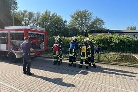 Ausbilder der Feuerwehr und Lehrgangsteilnehmer draußen vor dem Löschteich.