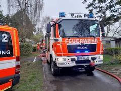 Feuerwehrfahrzeuge stehen auf einem Weg, Daneben liegt ein Schlauch.