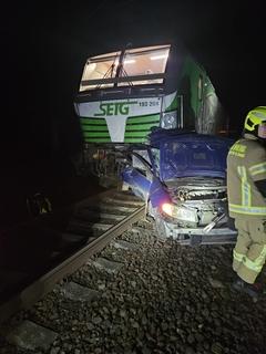 Lok und PKW auf Schiene im Dunkeln