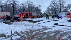 Feuerwehrautos und ein Polizeiauto im Schnee. Davor stehen Feuerwehrmänner im Schnee.