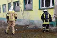 Rauch tritt aus Keller, davor zwei Feuerwehrmänner.