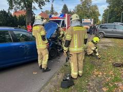 Feuerwehrläute stehen am Auto, das demoliert ist aufgrund eines Unfalls