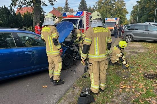 Feuerwehrläute stehen am Auto, das demoliert ist aufgrund eines Unfalls