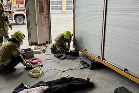 2 Feuerwehrmänner arbeiten am hydraulischem Rettungsgerät am Container.