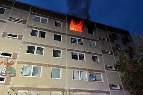 Gebäude bei dem aus einem Fenster sichtbar Flammen schlagen
