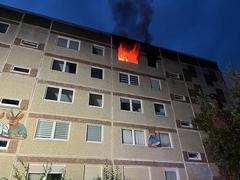 Gebäude bei dem aus einem Fenster sichtbar Flammen schlagen