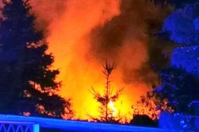 Rauchwolke mit roten Flammen. Davor ein Zaun.