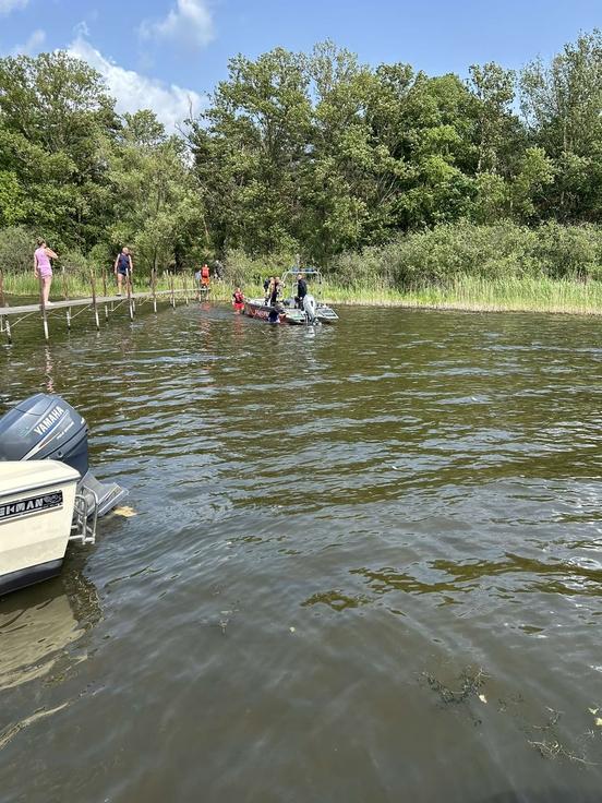 Bild vom Wasser aus auf einen Steg gerichtet. Auf dem Steg sind Personen und es befindet sich ein Rettungsboot auf dem Wasser
