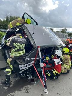 Auto steht schräg und Feuerwehrmänner über daran