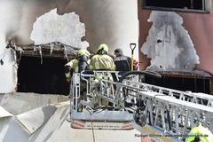 Zwei Feuerwehrmänner auf der DL mit einem Polizisten am Fenster
