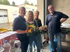 Drei Frauen bekommen Blumen und ein Mann steht daneben