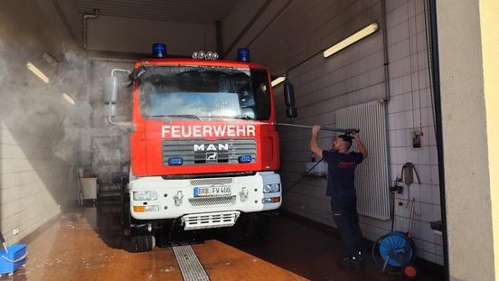 Feuerwehrmann kärchert Feuerwehrauto ab